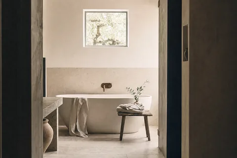 A freestanding bath below a small window, seen through an open doorway (example photo)